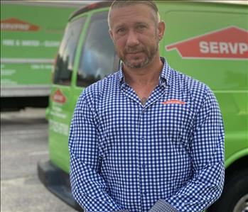 male SERVPRO employee smiling in front of green trucks